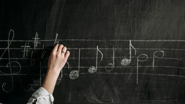 hand writing music notes on chalk board